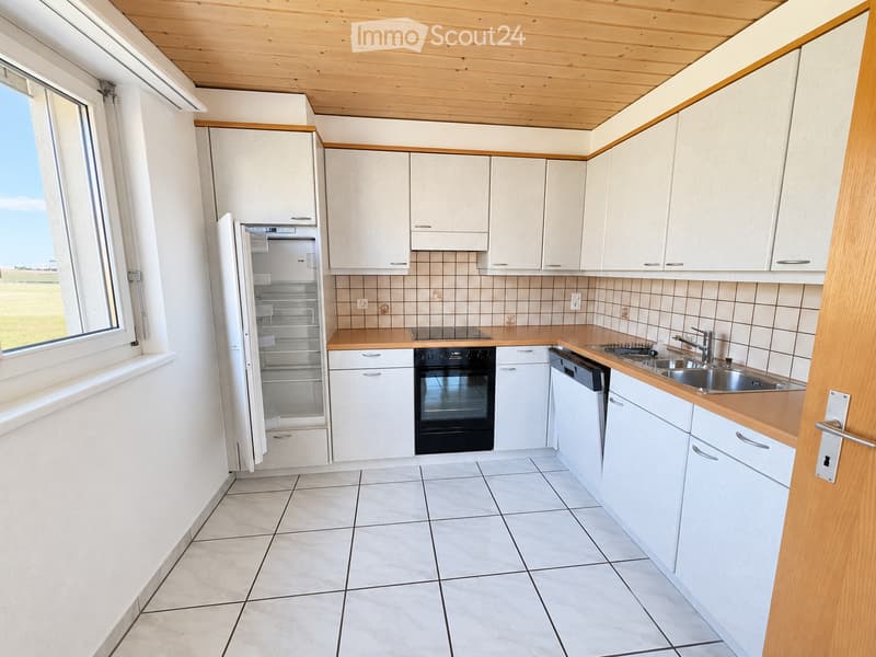 Modern kitchen with white cabinets, light wooden countertops, tiled backsplash, and stainless steel appliances including a refrigerator, oven, dishwasher, and sink.