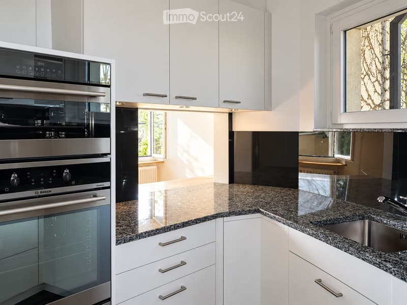 Modern kitchen with white cabinets, granite countertops, stainless steel oven, and sink.