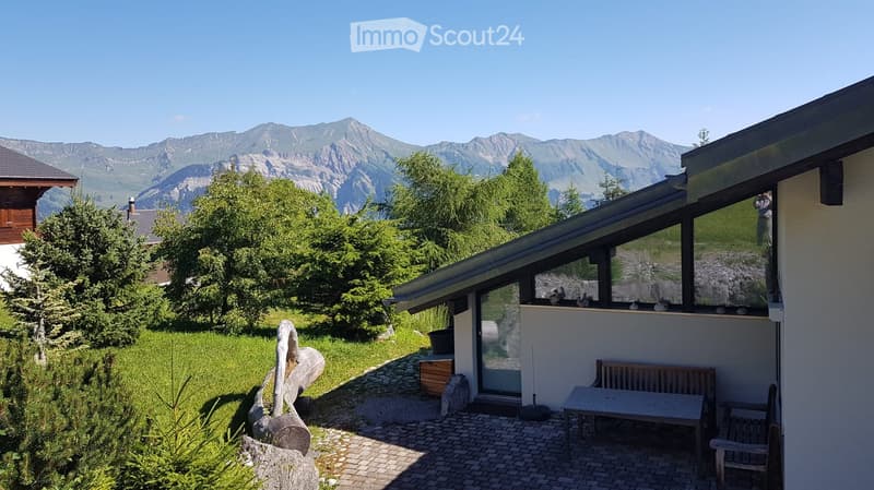 Outdoor patio area with a table, bench, and scenic mountain view in the background.