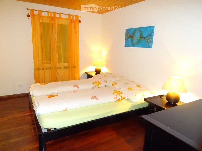 Cozy bedroom with a double bed, nightstands, table lamps, and a painting on the wall.