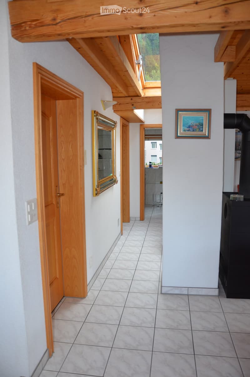Bright hallway with wooden doors, tiled floor, and exposed wooden beams on the ceiling. Features a mirror on one wall and a framed picture on the other.