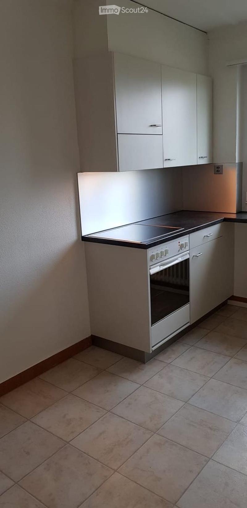 Modern kitchen with white cabinets, a built-in oven, and tiled flooring.