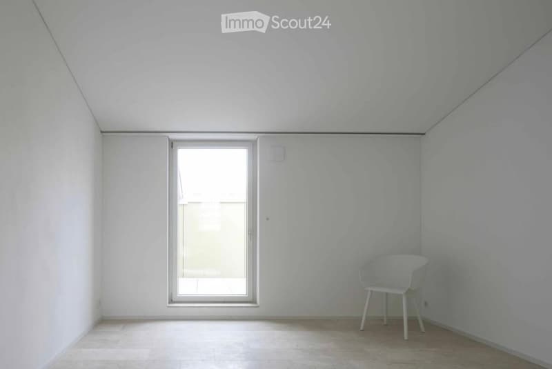 Minimalist room with white walls, tiled floor, and a single white chair near a large window opening to a balcony.