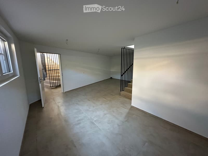 Empty hallway with tiled floor, white walls, and a staircase leading upwards. Natural light from a window on the left side.