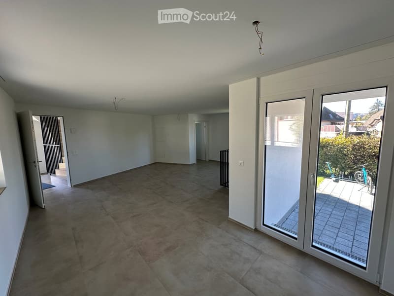 Empty room with tiled floor, white walls, large sliding glass doors leading to a patio, and an open doorway to another room.