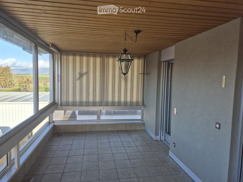 Spacious balcony with tiled floor, large windows, and a hanging lantern-style light fixture.