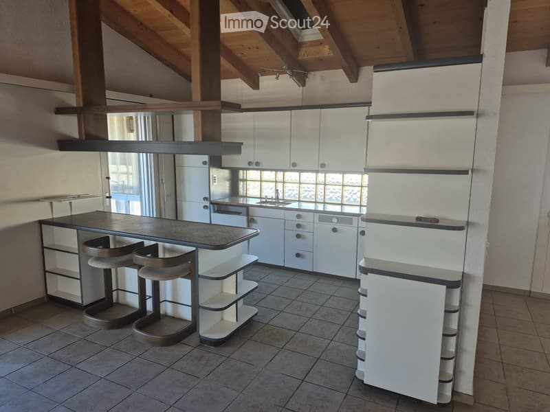 Modern kitchen with white cabinets, stainless steel appliances, a central island with bar stools, and a sink area with a window above.