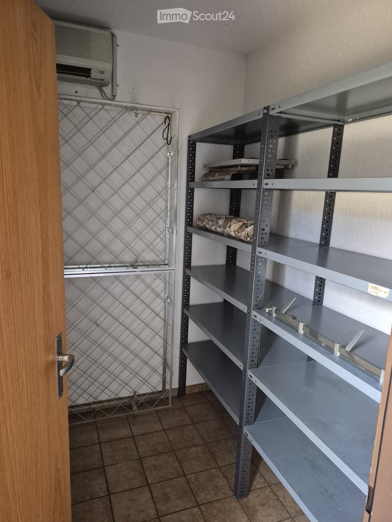 Empty storage room with metal shelving units and a tiled floor. The shelves are mostly empty, with a few items stored on them.