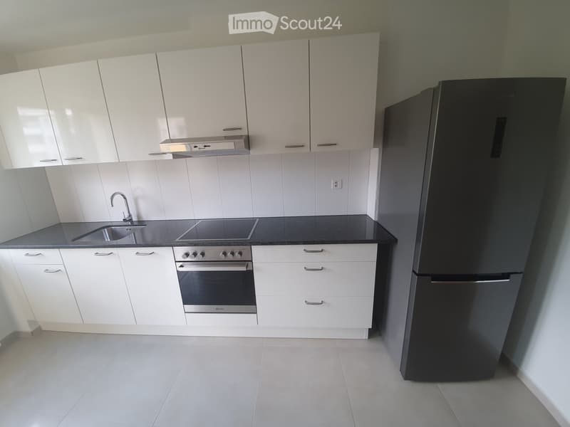 modern kitchen with white cabinets, black countertops, stainless steel appliances, and tiled flooring