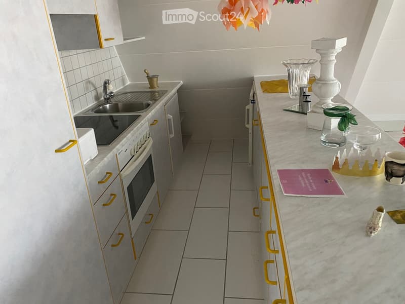 Compact kitchen with white cabinets, yellow accents, tile flooring, sink, and a dishwasher
