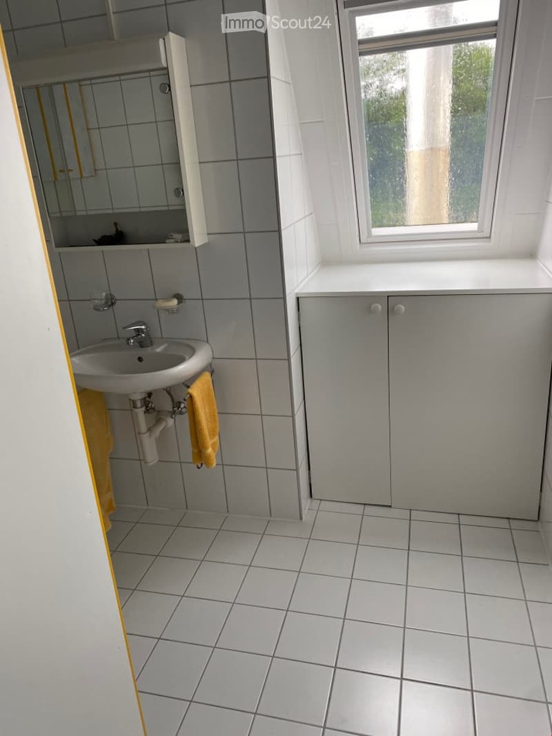 Tiled bathroom with a sink, mirror cabinet, and a window