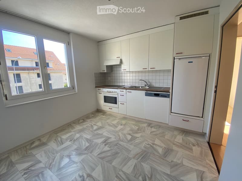 Modern kitchen with white cabinets, marble tiled floor, and stainless steel appliances including a refrigerator, oven, and dishwasher.