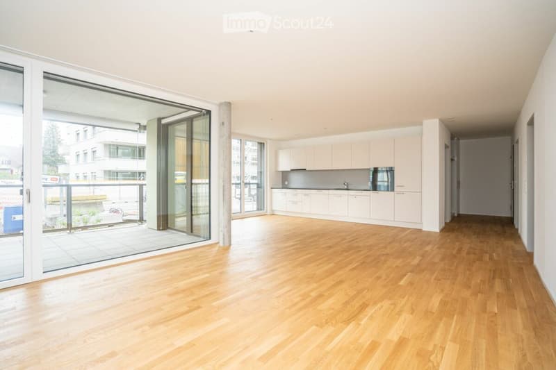 Empty room with light wooden flooring, white cabinetry, and large glass sliding doors leading to an outdoor area.