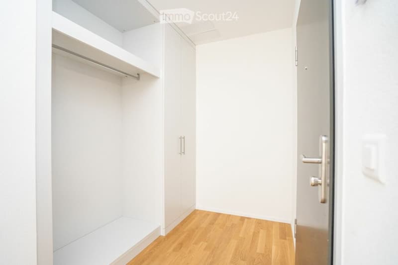 Empty room with white walls, wooden floor, and built-in closet with shelves and hanging space.