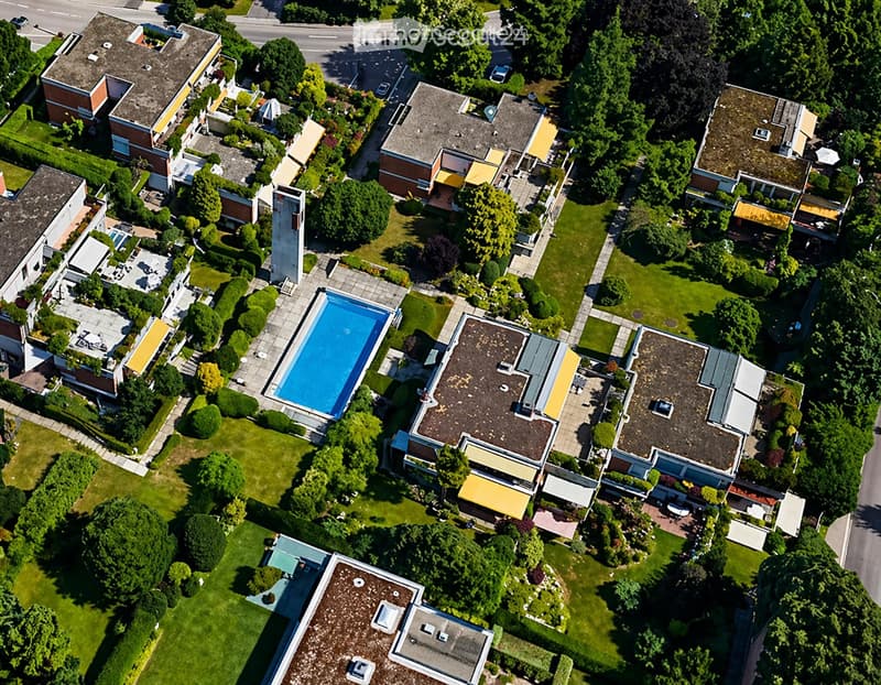 Aerial view of a residential area with multiple houses, a swimming pool, and well-maintained gardens.