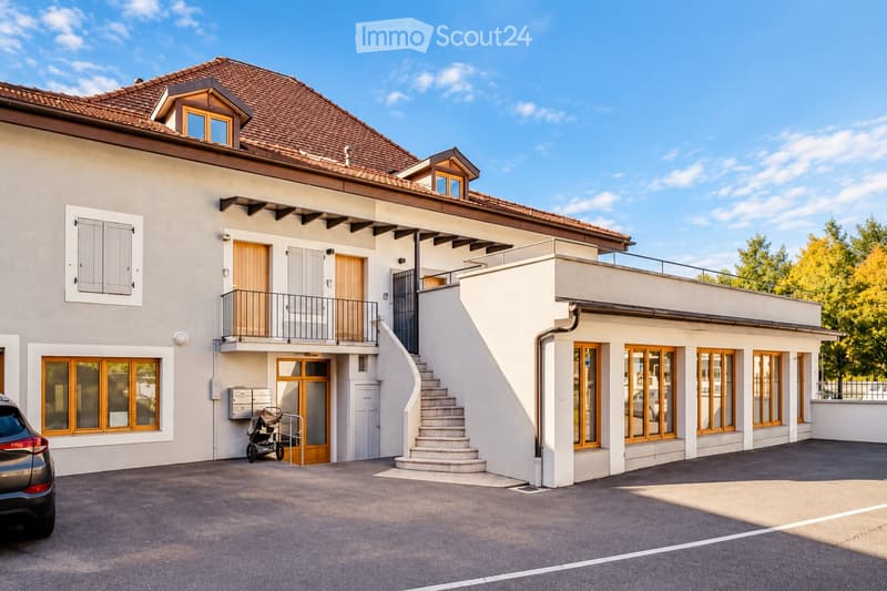 Two-story house with a tiled roof, multiple windows, a balcony, and a raised ground floor entrance with steps.