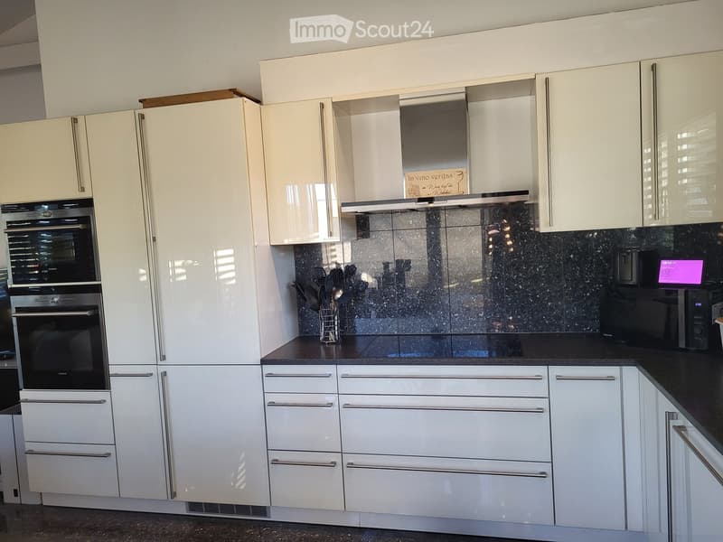 Modern kitchen with white cabinets, stainless steel appliances, and a black granite countertop.