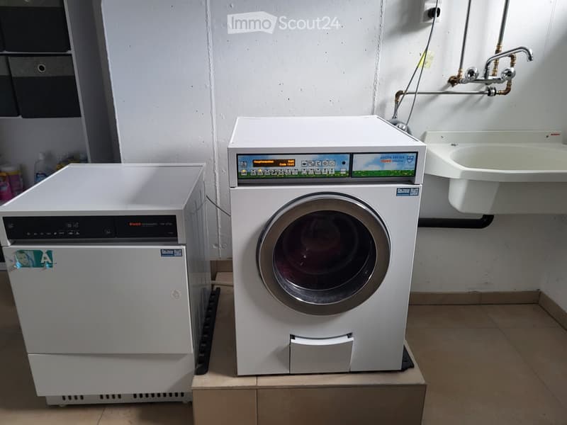 Bathroom with a washing machine and a sink, white tiled walls, and a tiled floor.