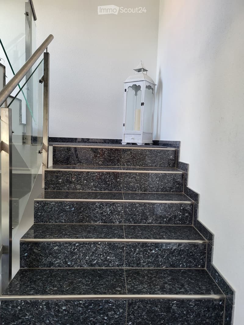Staircase with dark granite steps, metal handrail, and a white decorative lantern on the landing.