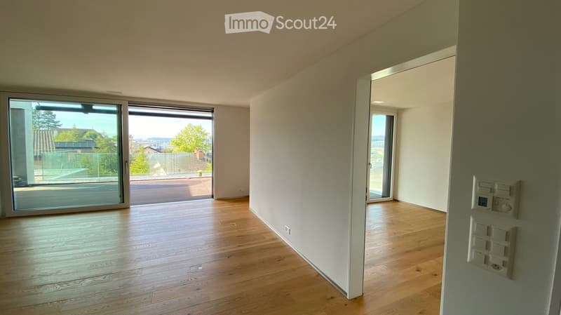 Empty room with wooden flooring, large sliding glass doors, and light-colored walls.