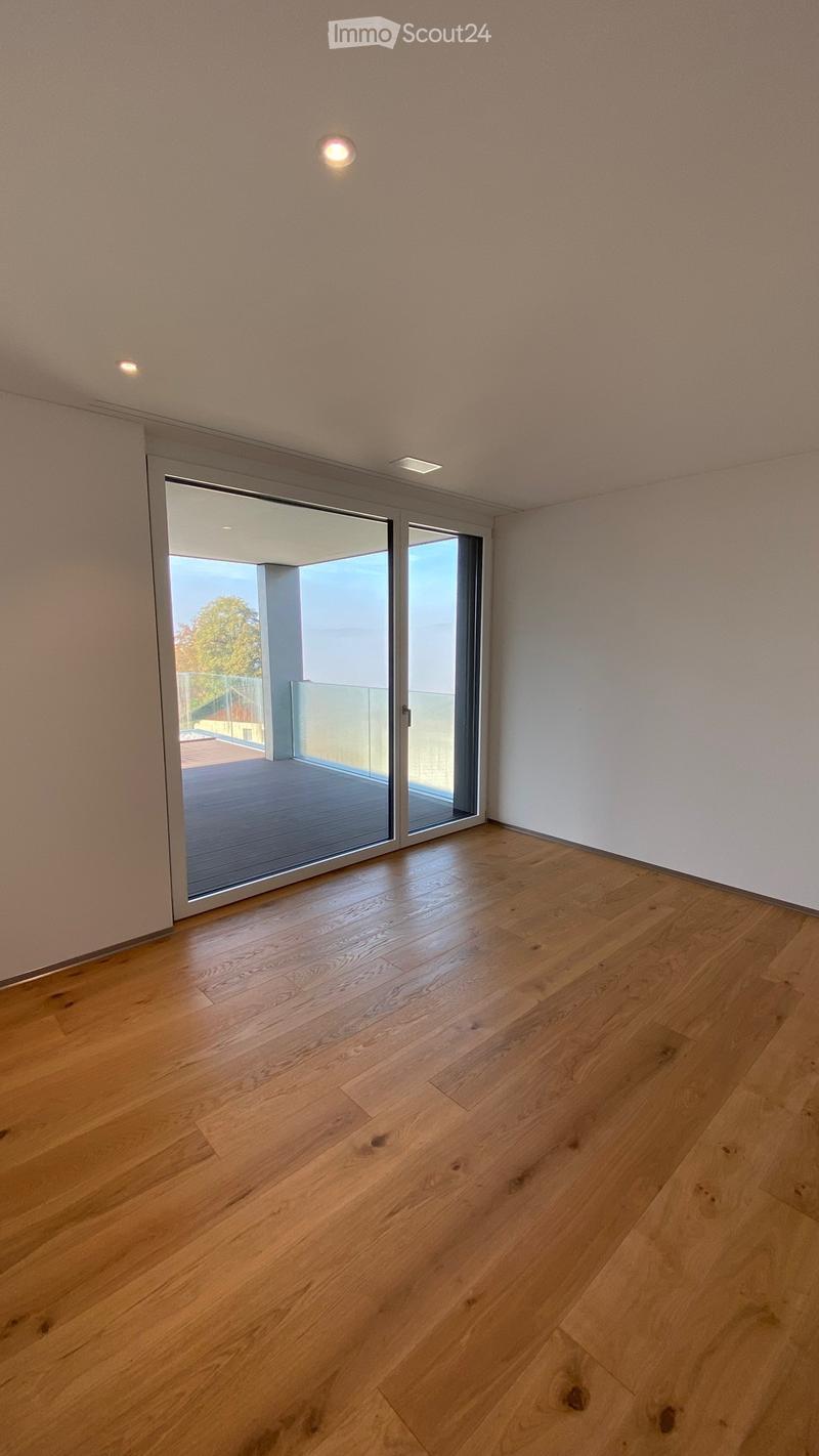 Empty room with light wooden flooring, white walls, and a large sliding glass door leading to a balcony or terrace area.