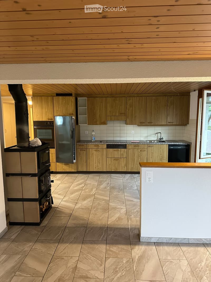 Modern kitchen with wooden cabinets, granite countertops, and a tiled floor. Features include a refrigerator, oven, dishwasher, and sink.