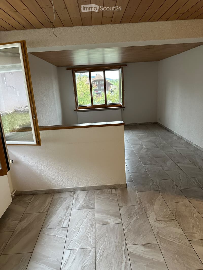 Empty room with tiled flooring, wooden ceiling, and large windows offering a view of the outdoors.