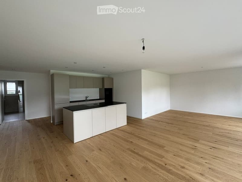 Modern, minimalist kitchen with light-colored cabinets, a central island, and a sleek sink. The space features light wooden flooring and ample natural light.