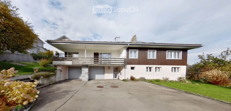 Two-story house with a modern design, featuring a garage, balcony, and well-maintained garden.