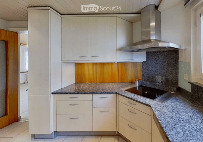 Modern kitchen with white cabinets, granite countertops, a built-in stove, and a stainless steel range hood.