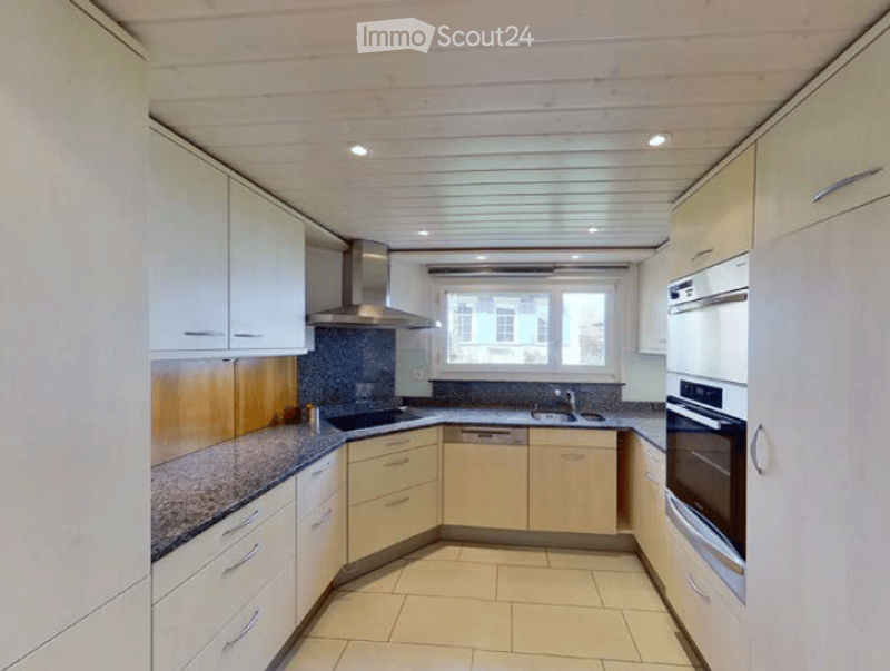 Modern kitchen with white cabinets, granite countertops, stainless steel appliances, and a large window.