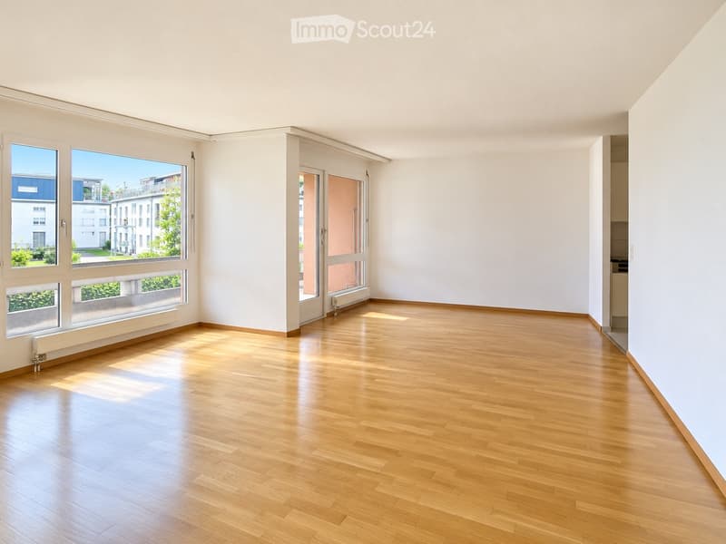 Empty room with wooden flooring, large windows, and white walls. No furniture or equipment present.