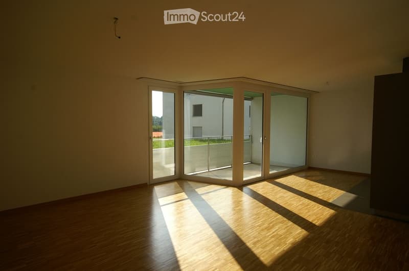 Empty room with wooden flooring and large sliding glass doors leading to a balcony area.