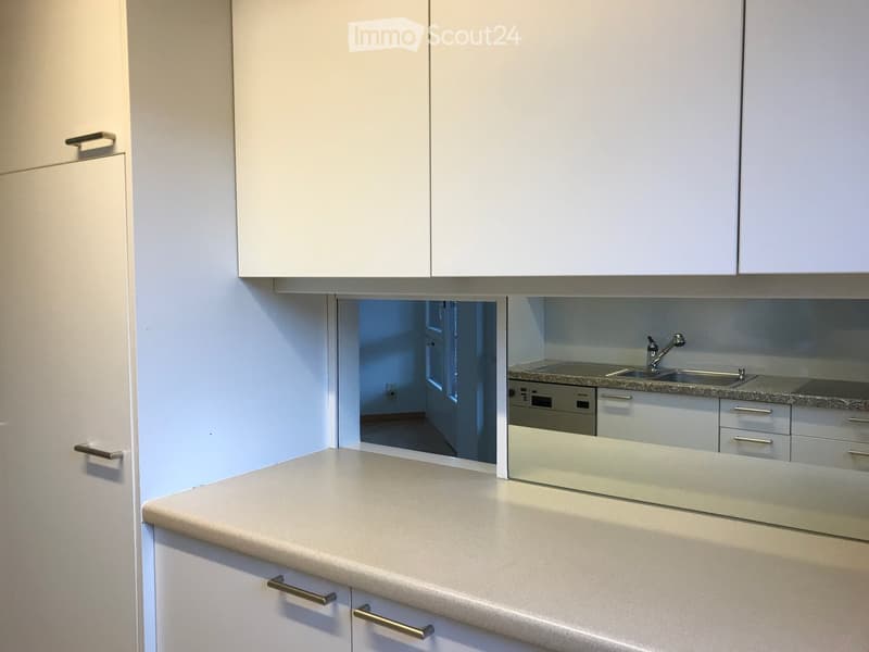 Modern kitchen with white cabinets, granite countertop, and stainless steel sink and dishwasher.