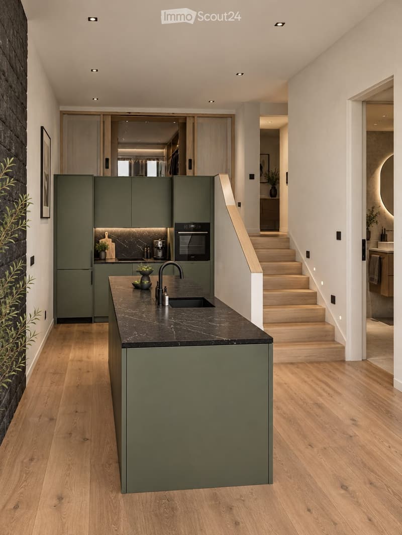 Modern kitchen with green cabinets, marble countertop, wooden flooring, and built-in appliances including an oven and coffee maker. A staircase leads to an upper level.