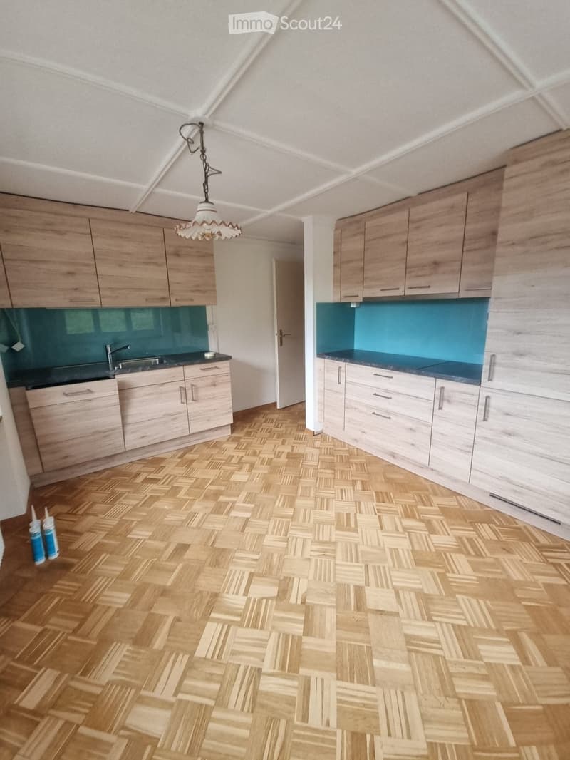 Empty kitchen with wooden floor, wooden cabinets, blue countertops, a sink, and a faucet