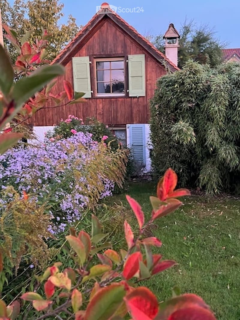 2-story wooden house, green shutters, red chimney, garden with purple flowers and red plants