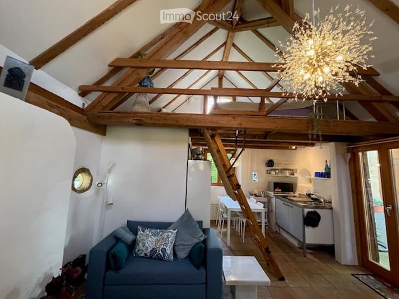 wooden beam ceiling, sofa, wooden ladder, chandelier, kitchen with sink and cabinets