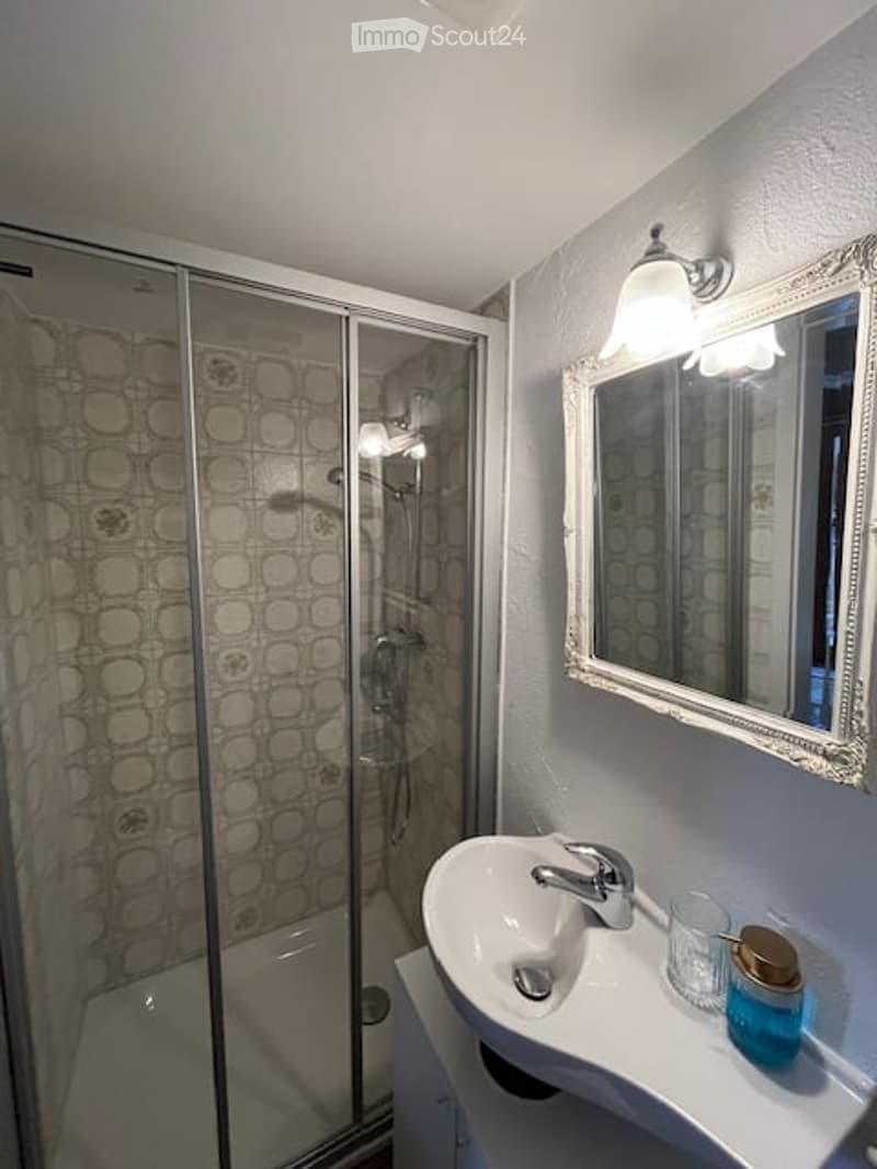 Bathroom with shower enclosure, sink, mirror, and a white tile design on the wall