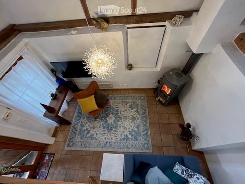 small living room with fireplace, wooden beams, chandelier, rug, sofa, and armchair