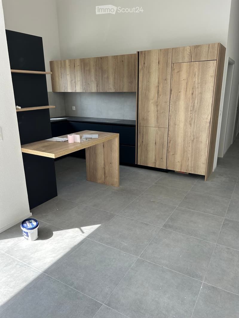 Empty kitchen with wooden cabinets, a wooden countertop, and grey tiled flooring. No appliances or furniture are present.