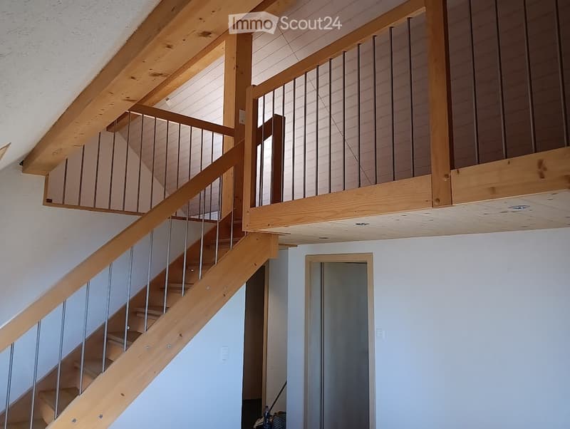 Raised ground floor, wooden stairs, white walls, white ceiling, wooden handrail, metal railing