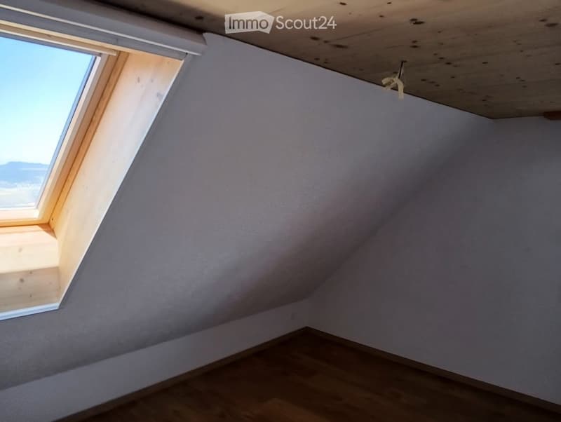 angled white walls, wooden floor, slanted ceiling, small window