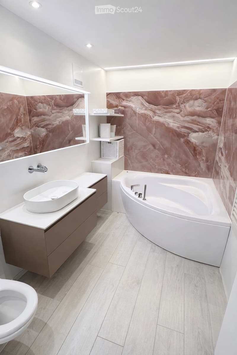 Modern and spacious bathroom with a bathtub, white sink, and large mirror.