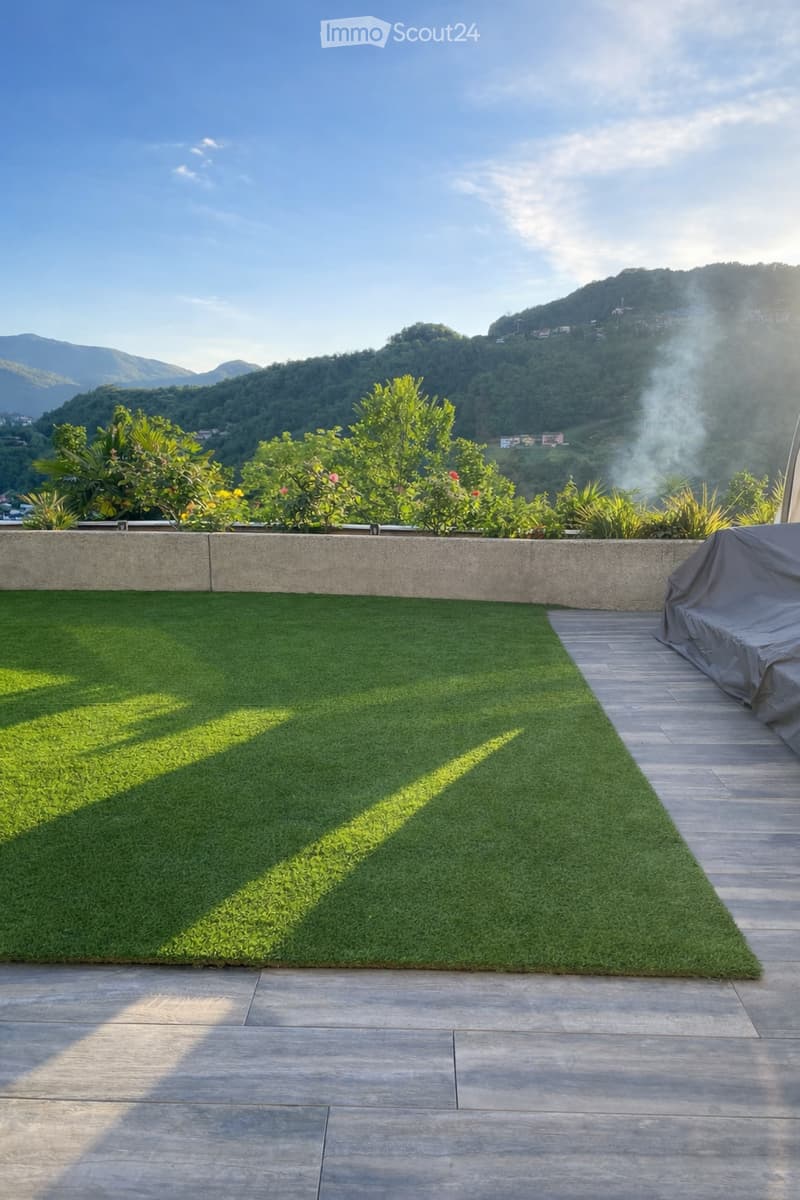 Balcony with wooden floor and artificial grass, concrete wall, mountain view