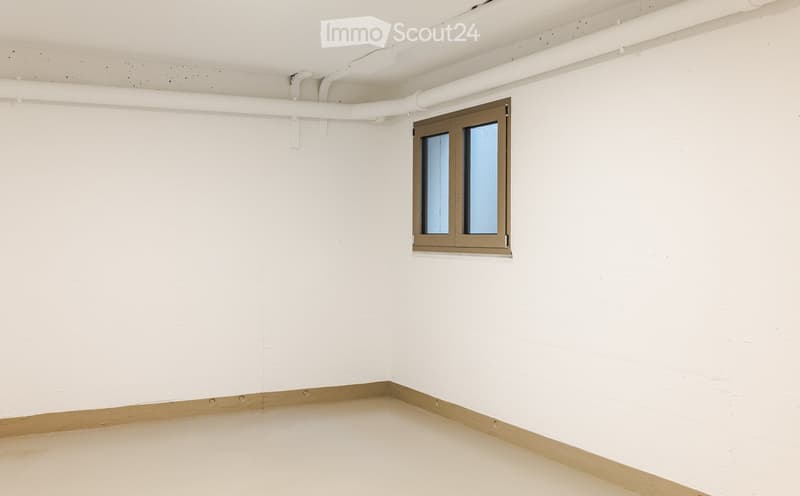 Empty room with white walls, a single window with a brown frame, and a smooth concrete floor.