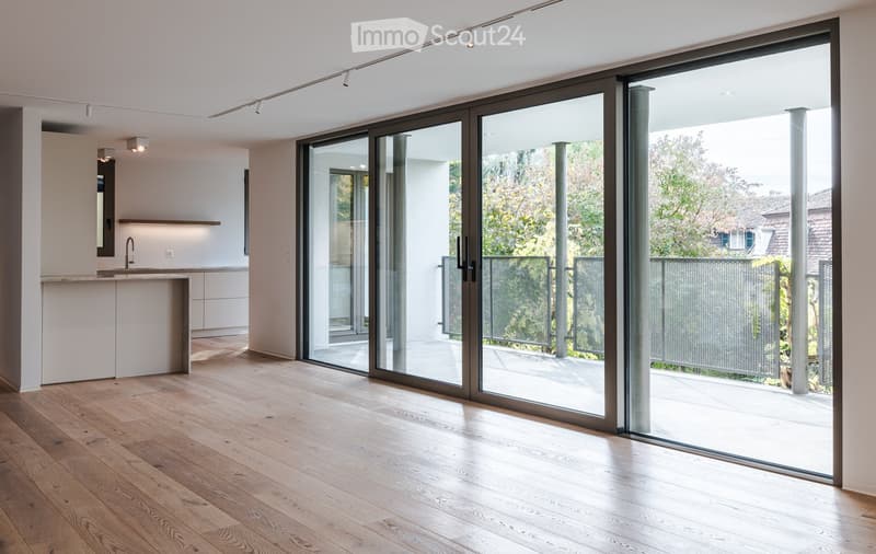 Modern kitchen with light-colored cabinets, a central island, and large sliding glass doors leading to an outdoor area.