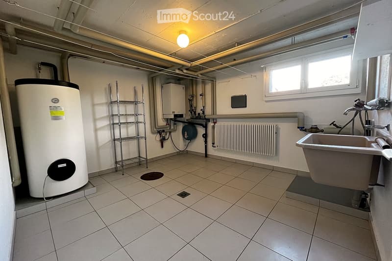 Utility bathroom with tiled floor, white walls, a sink, radiator, water heater, and metal shelf.