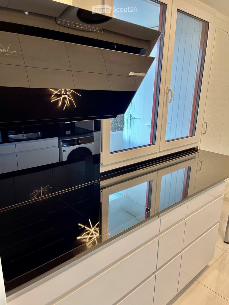 Modern kitchen with white cabinets, stainless steel oven, and a washing machine visible in the background.