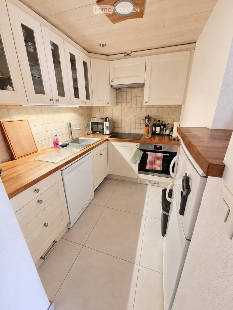 Modern kitchen with white cabinets, wooden countertops, stainless steel appliances, and a clean, organized layout.